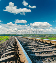 Naklejki Tory kolejowe i błękitne niebo z chmurami na horyzoncie
