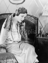 Naklejki Young woman sitting on her bed in the bed room, speaking on the telephone 