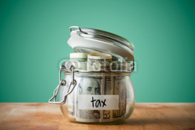 Fototapety Dollar bills in glass jar isolated on a green background. Saving money concept for tax. 
