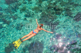 Naklejki Woman snorkeling in clear tropical waters above coral reef