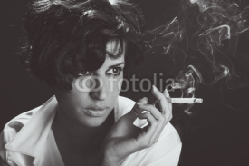 Obrazy i plakaty Elegant brunette woman smoking a cigarette on black background
