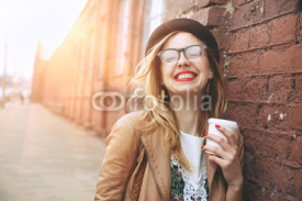 Naklejki Cheerful woman in the street drinking morning coffee in sunshine