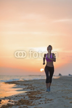 Naklejki Fitness young woman running on beach in the evening