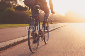 Naklejki Young woman cycling in the park at sunset