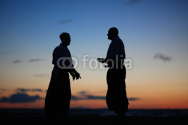 Naklejki Silhouettes of two men speaking at sunset