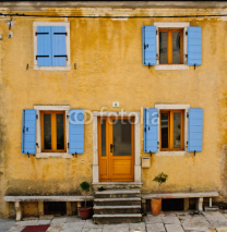 Fototapety Front of an old house with blue shutters and yellow wall