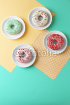 Naklejki Plates with delicious donut on colorful background