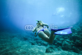 Fototapety A woman floats in the ocean with fins in the background of pitfalls. Rear view under water