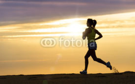 Naklejki Athlete running at sunset on beach