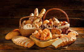 Obrazy i plakaty Variety of bread in wicker basket on old wooden background.