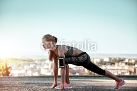 Fototapety Portrait of woman athlete ready to start jogging, standing in runner position on rocky terrain. Concept of sport, competition and success. 