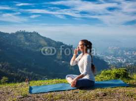 Fototapety Woman practices pranayama in lotus pose outdoors
