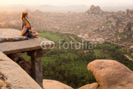 Naklejki Young woman meditating at mountain cliff on sunrise