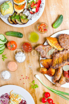 Fototapety High Angle View of Grilled Meal of Steak, Chicken and Vegetables Spread Out on Rustic Wooden Table