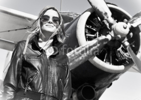 Naklejki Young beautiful woman pilot in front of  airplane.