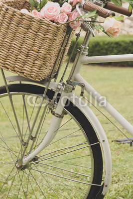 Vintage bicycle on the field with a basket of flowers