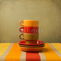 Fototapety Stack of colorful coffee cups on tablecloth or place mat