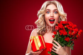 Beautiful blonde woman holding bouquet of red roses and gift. Saint Valentine and International Women's Day, Eight March celebration.