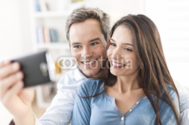 Naklejki cheerful couple taking a selfie with a smartphone