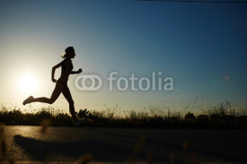 Fototapety Silhouette of athletic girl running down the road to a sunset
