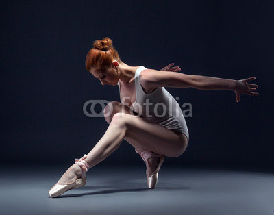 Graceful slender ballerina dancing in studio