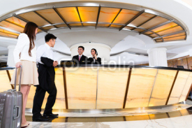 Asian Chinese couple arriving at hotel front desk
