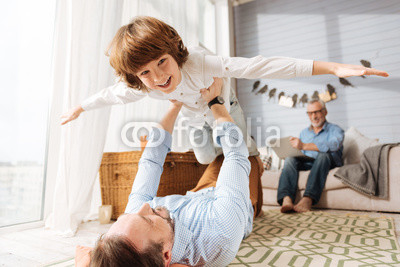 Happy cute boy being held by his father