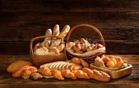 Fototapety Variety of bread in wicker basket on old wooden background.