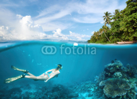 Naklejki Young woman snorkeling in clear tropical waters in near of exotic island.