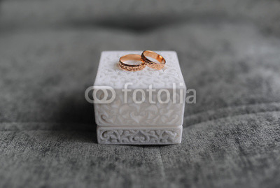 Wedding ring in white cube on grey background