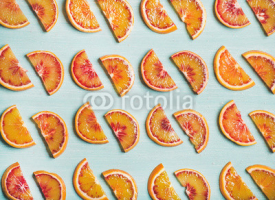 Natural fruit pattern concept. Fresh juicy blood orange slices over light blue painted table background, top view