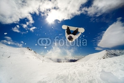 Snowboarder going off jump doing a backflip