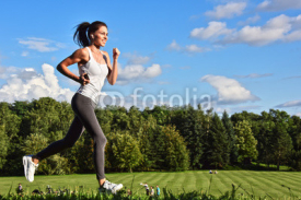 Naklejki Young woman running in the park during sport training