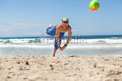 erwachsener junger sportlicher mann spielt beachvolleyball