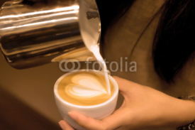 Naklejki Hand pouring milk to do Latte art