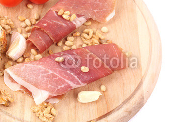 Prosciutto with tomatoes on wooden platter.