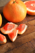 Naklejki Ripe grapefruits on cutting board, on wooden background
