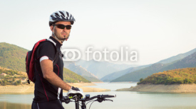 Naklejki Mountain biker beside a beautiful lake