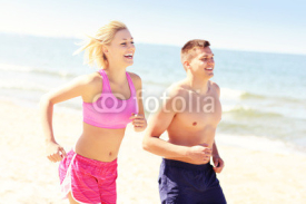 Naklejki Young couple jogging along the beach