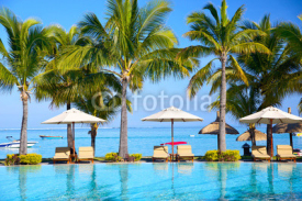 Naklejki Swimming pool with  umbrellas on beach in Mauritius