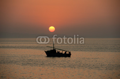 Sunset over the ocean with a boat