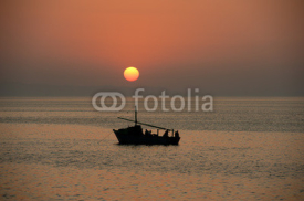 Sunset over the ocean with a boat