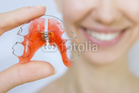 Fototapety Smiling girl holding braces for teeth