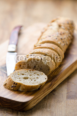 bread with seeds on a wooden board and knife