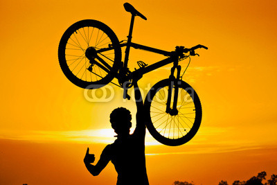cyclist raising his bike with thumbs up silhouette
