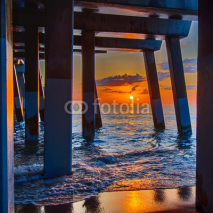 Fototapety The rising sun peeks through clouds and is reflected in waves by