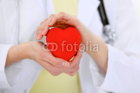 Obrazy i plakaty Female doctor with stethoscope holding heart.  Patients couple sitting in the background