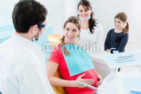 Zahnarzt mit schwangerer Frau und Kind in Praxis samt Sprechstundenhilfe
