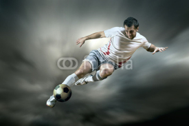 Obrazy i plakaty Football player with ball on field of stadium
