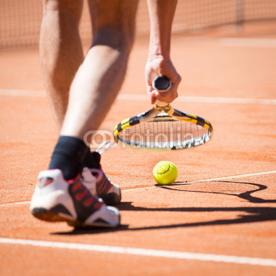 sportsman catchs up his tennis ball with racket